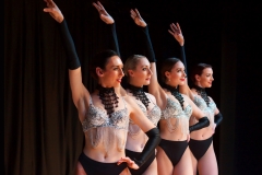 Four female dancers in silver and black costumes