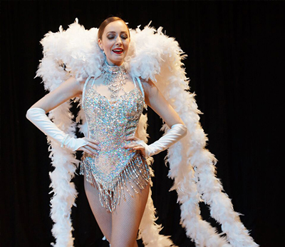 Female performer in silver and white costume with feather collar