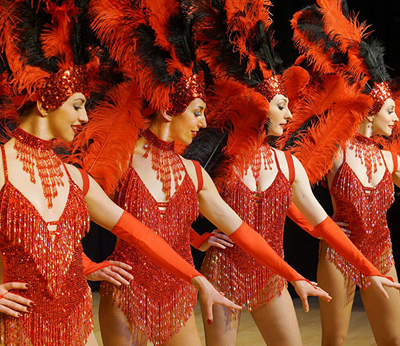 Four female performers in red costumes and feather head pieces